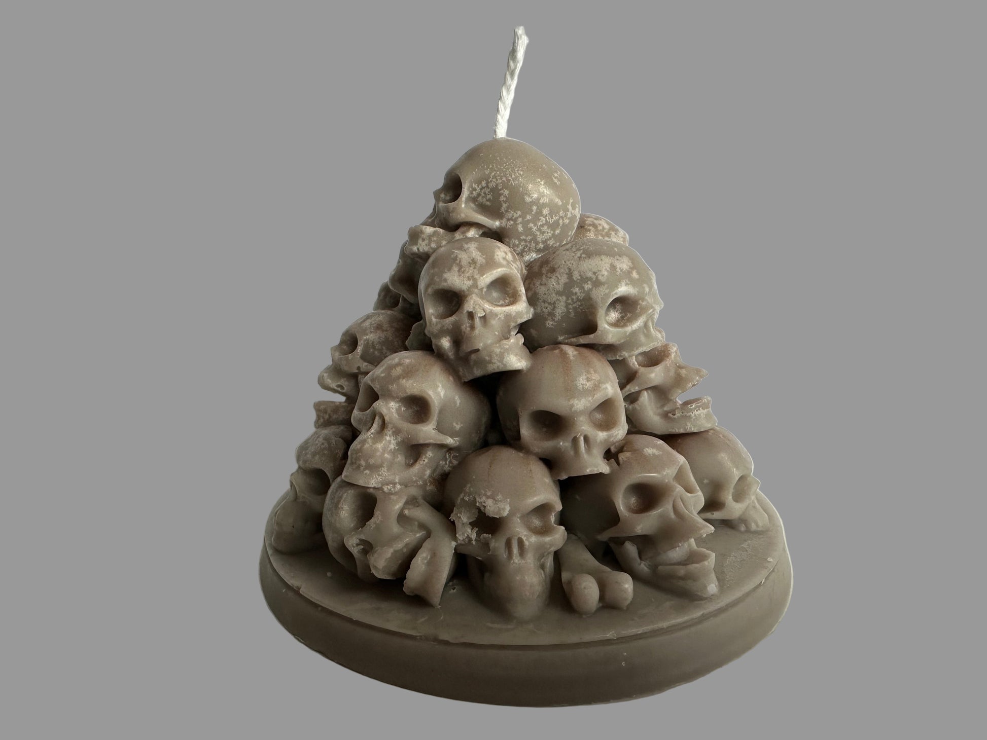 Candle in the shape of a pyramid made of skulls on a white background